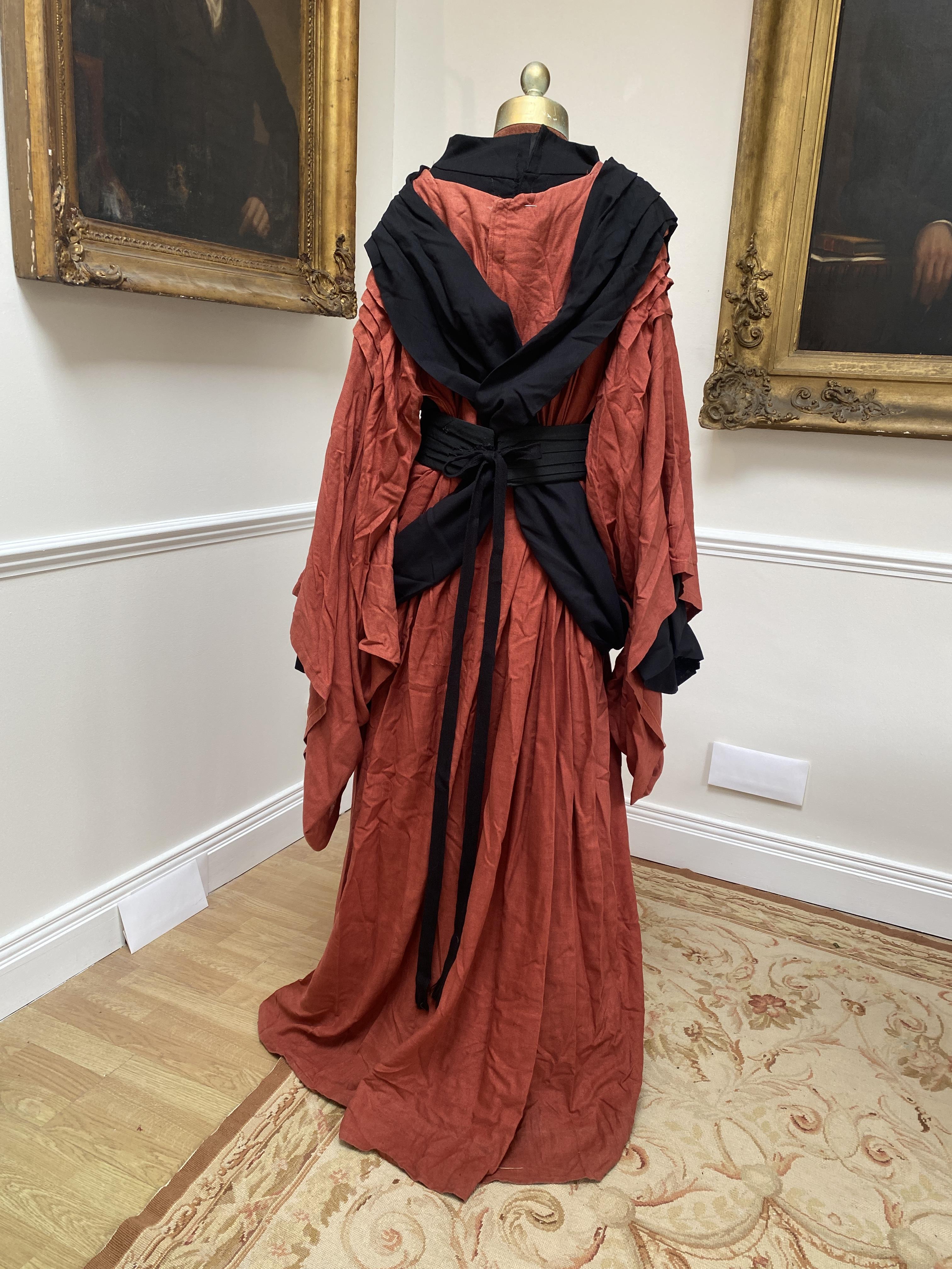 A men’s Buddhist style robe in rust linen, with black under-garment and black decorative belt, labelled Glyndebourne Festival Opera (Idomeneo)